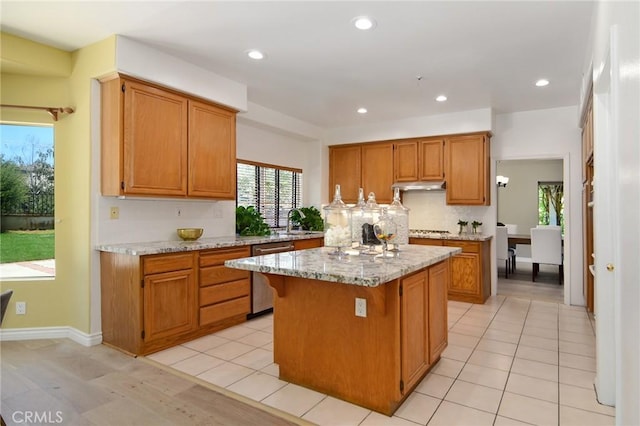 kitchen featuring a center island, dishwasher, light hardwood / wood-style flooring, light stone counters, and sink