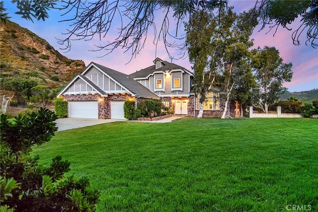 view of front facade with a garage, a mountain view, and a yard