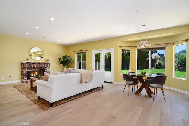 living room with a wealth of natural light, a fireplace, and light hardwood / wood-style flooring