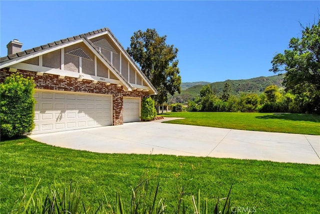 view of property exterior with a mountain view, a yard, and a garage