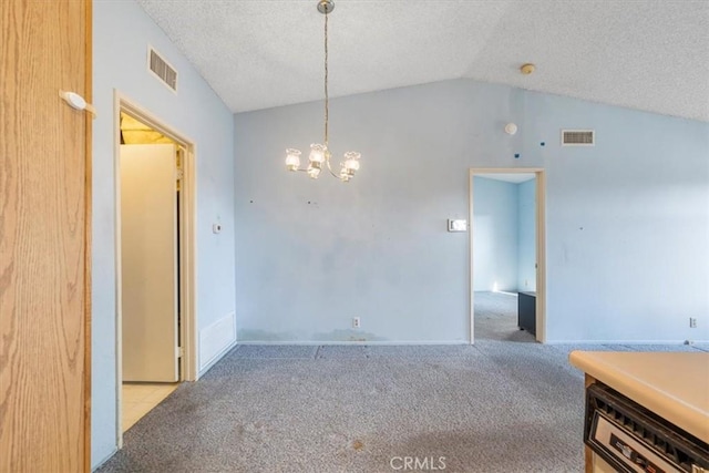 carpeted spare room with a textured ceiling, a chandelier, and vaulted ceiling