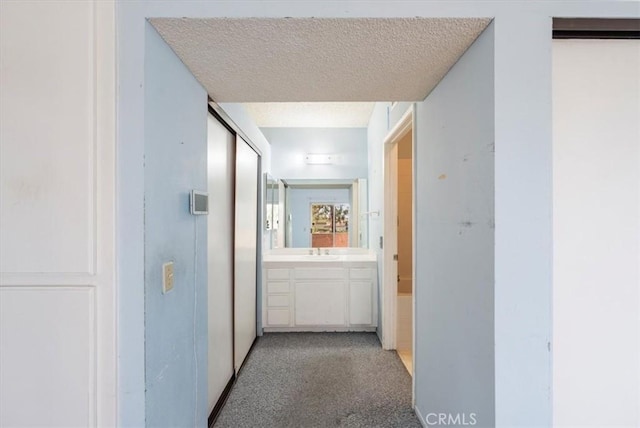 corridor with a textured ceiling and sink