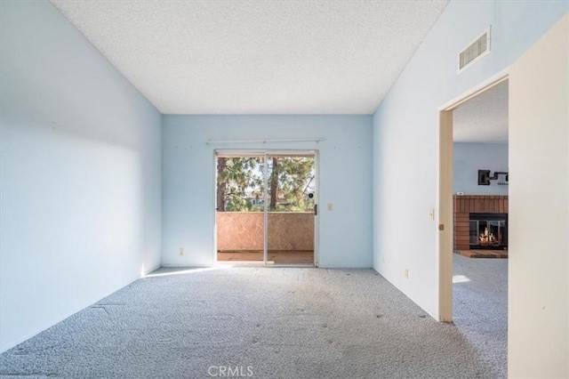 unfurnished room with light carpet, a textured ceiling, and a fireplace