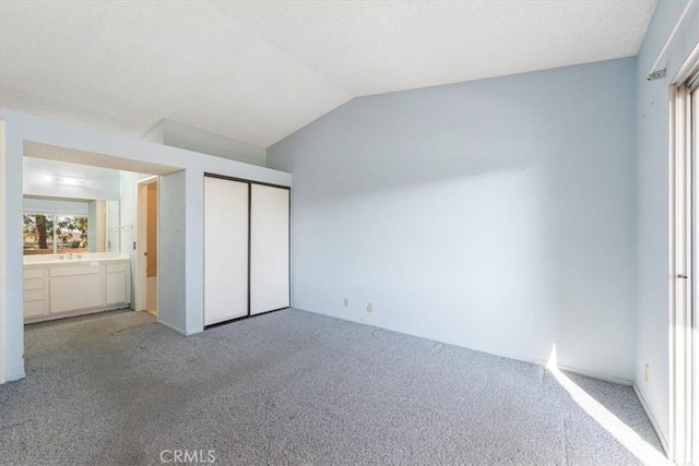 unfurnished bedroom featuring light colored carpet, a closet, and lofted ceiling