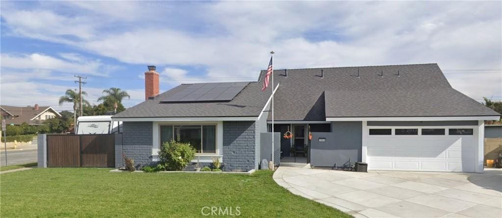 view of front of property featuring a garage, solar panels, and a front yard