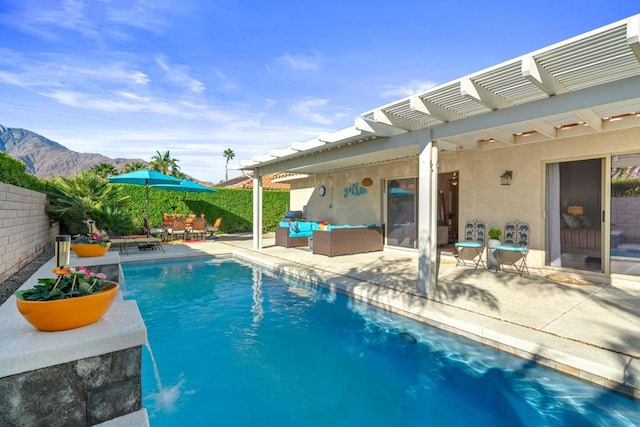 view of swimming pool featuring pool water feature, outdoor lounge area, a mountain view, and a patio