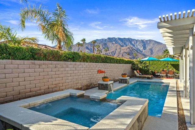 view of swimming pool with pool water feature, a mountain view, and an in ground hot tub