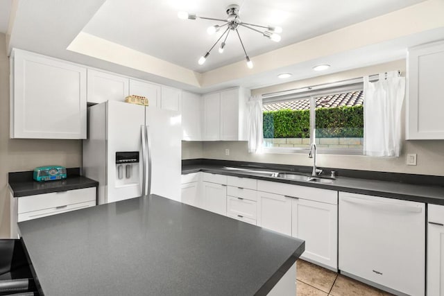 kitchen featuring sink, white appliances, white cabinets, and a notable chandelier