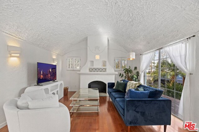 living room featuring lofted ceiling, brick ceiling, wood-type flooring, and a fireplace