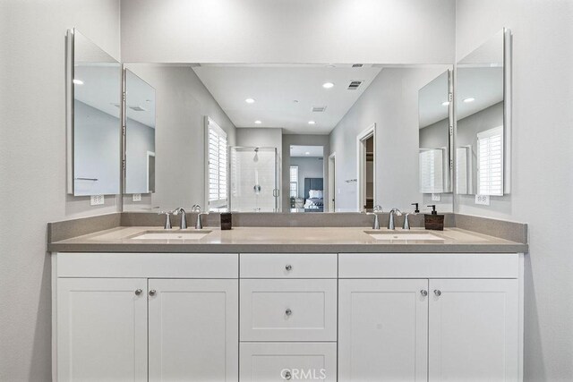 full bathroom featuring double vanity, a sink, visible vents, and a shower stall