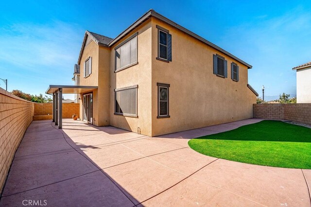 back of house featuring a fenced backyard, a patio, a lawn, and stucco siding