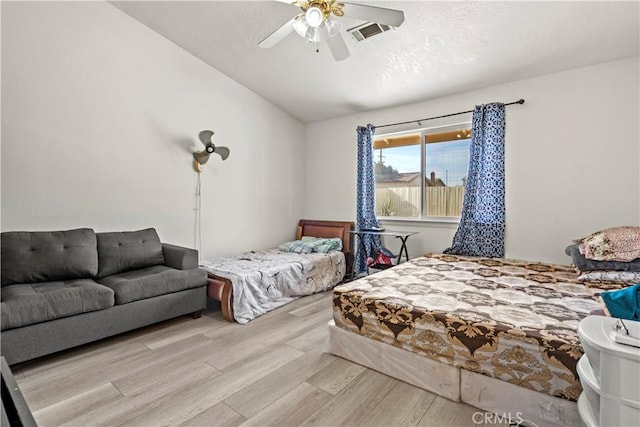 bedroom with ceiling fan, vaulted ceiling, and light wood-type flooring