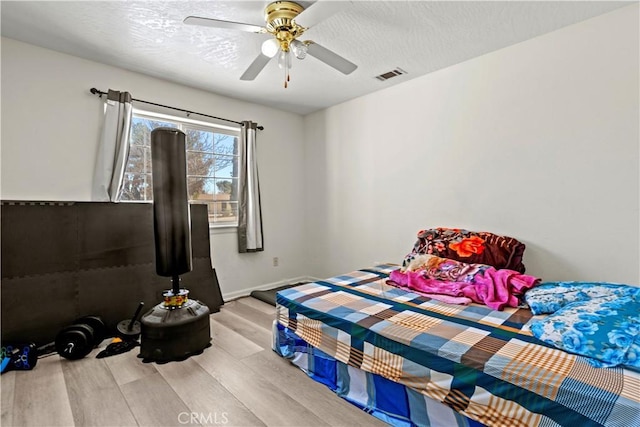 bedroom with ceiling fan, a textured ceiling, and light hardwood / wood-style floors