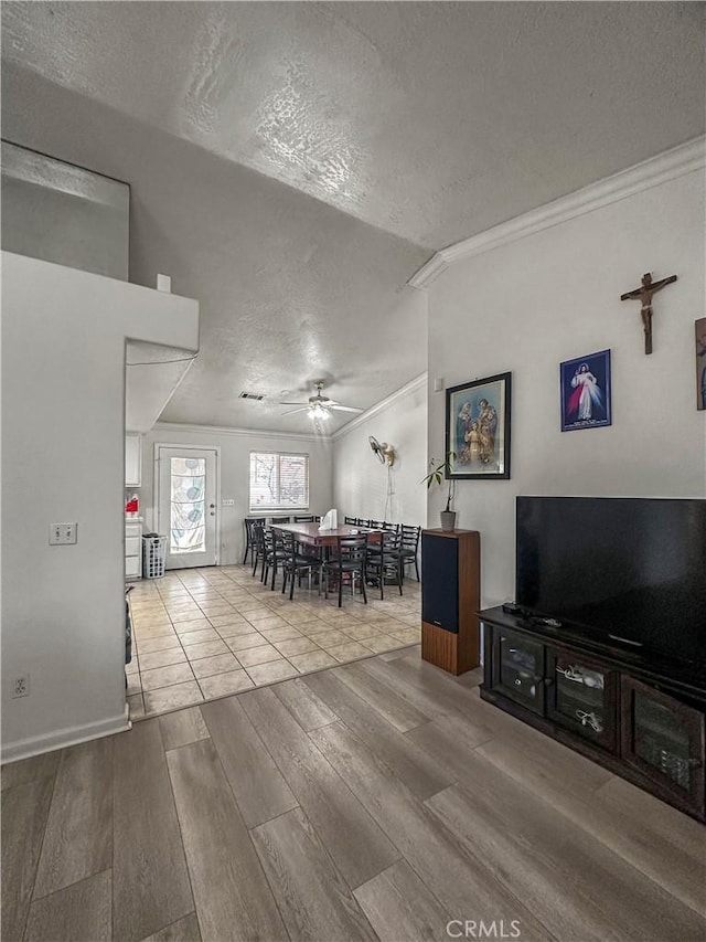 unfurnished dining area featuring ceiling fan, ornamental molding, a textured ceiling, and hardwood / wood-style flooring