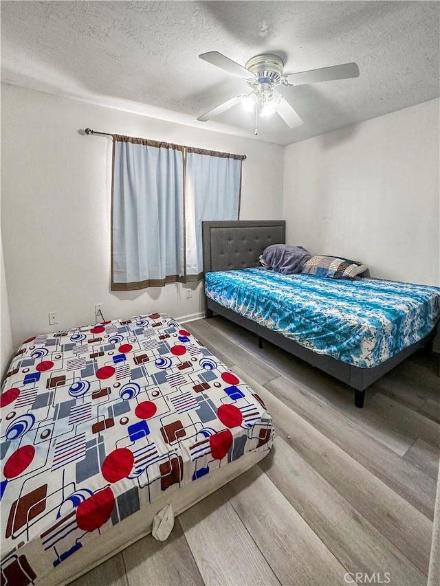 bedroom with a textured ceiling, ceiling fan, and hardwood / wood-style floors