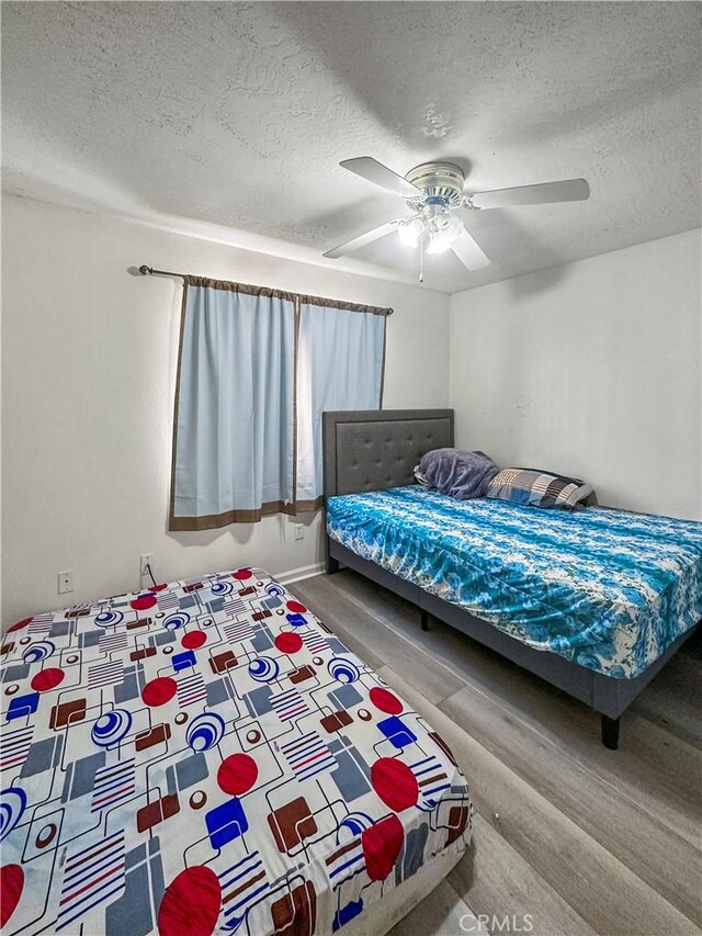 bedroom with ceiling fan, a textured ceiling, and hardwood / wood-style floors