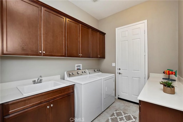 laundry room featuring washing machine and dryer, sink, and cabinets