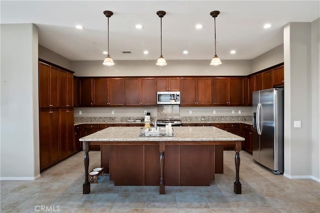 kitchen featuring stainless steel appliances, light stone counters, a breakfast bar, and a kitchen island