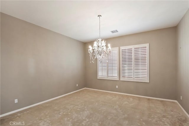 carpeted spare room featuring a chandelier