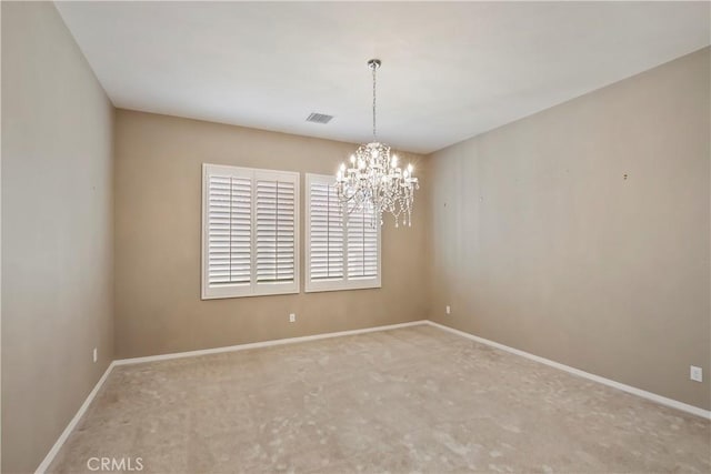 carpeted empty room featuring a chandelier