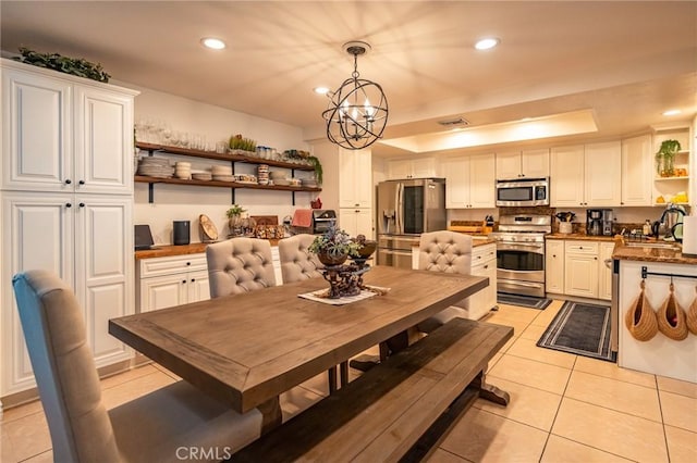 tiled dining area featuring sink, a raised ceiling, and a notable chandelier