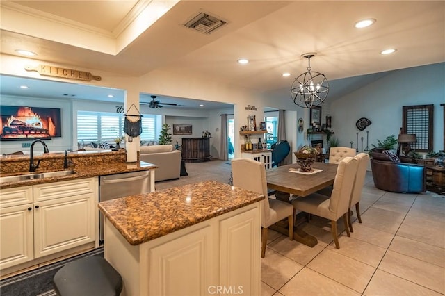 dining space with a raised ceiling, sink, light tile patterned flooring, ornamental molding, and ceiling fan with notable chandelier