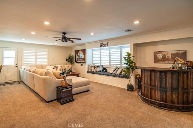 living room with ceiling fan, ornamental molding, and light carpet