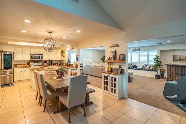 dining room featuring light carpet, vaulted ceiling, a notable chandelier, and sink