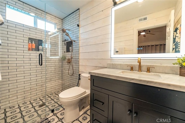 bathroom with toilet, wooden walls, ceiling fan, an enclosed shower, and vanity