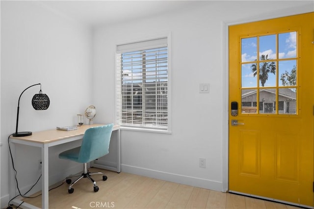 home office with a wealth of natural light and light hardwood / wood-style flooring