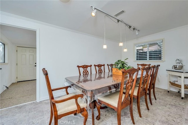 dining room with track lighting and ornamental molding