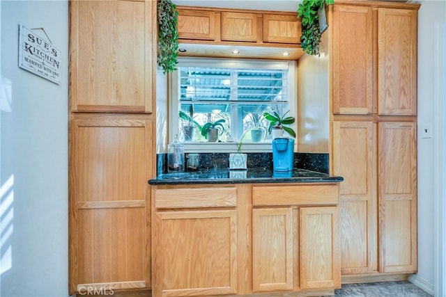 kitchen featuring light brown cabinetry and dark stone counters