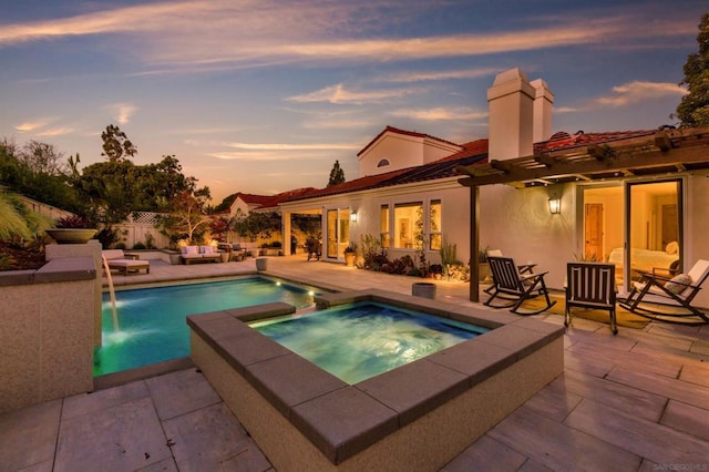 pool at dusk featuring a patio and an in ground hot tub