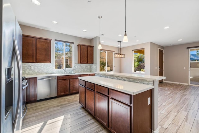 kitchen featuring a kitchen island, appliances with stainless steel finishes, a wealth of natural light, and decorative light fixtures