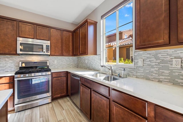 kitchen with stainless steel appliances, light hardwood / wood-style floors, sink, and backsplash