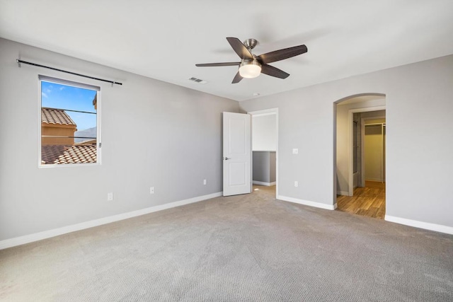 unfurnished bedroom with a walk in closet, carpet floors, and ceiling fan