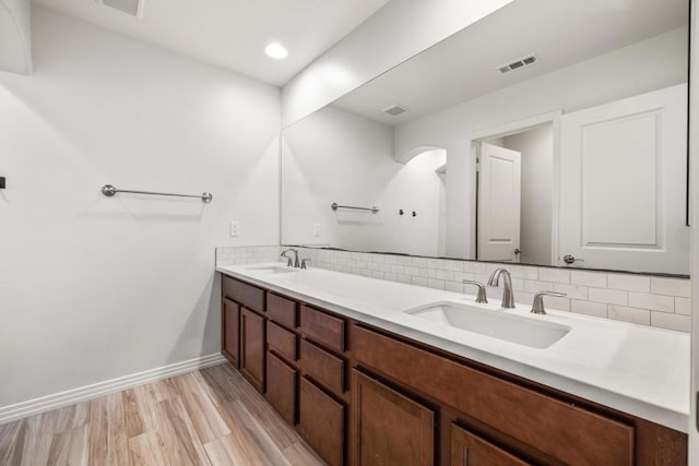 bathroom featuring vanity, wood-type flooring, and backsplash