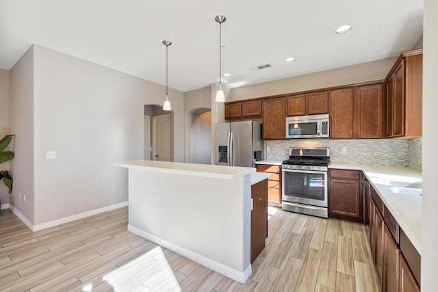 kitchen featuring a center island, hanging light fixtures, light hardwood / wood-style flooring, stainless steel appliances, and decorative backsplash