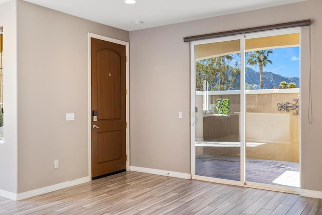 unfurnished room with a mountain view and light hardwood / wood-style floors