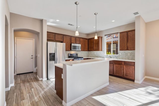 kitchen with a center island, light hardwood / wood-style flooring, pendant lighting, stainless steel appliances, and backsplash