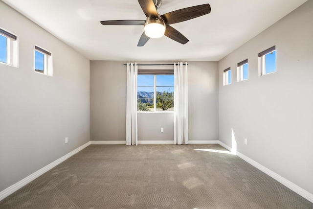 carpeted spare room featuring ceiling fan and plenty of natural light