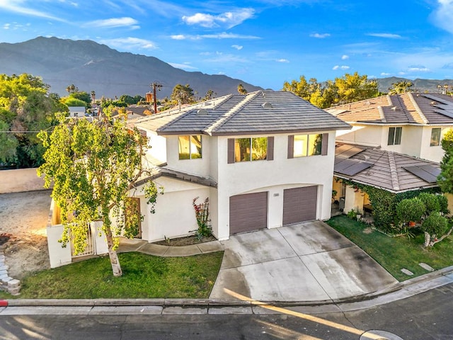 view of front facade featuring a front lawn, a mountain view, and a garage