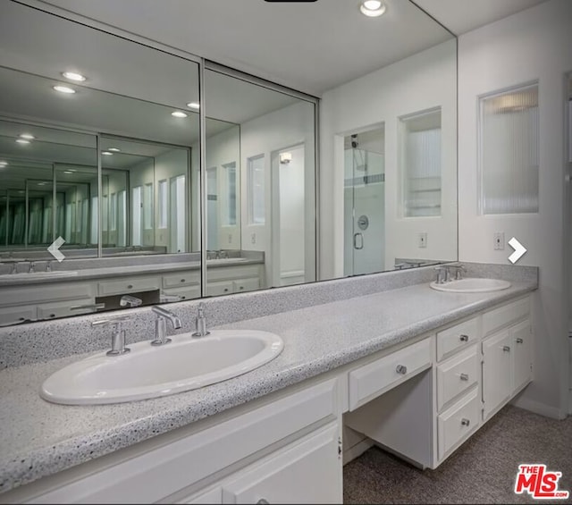 bathroom featuring a shower with shower door and vanity