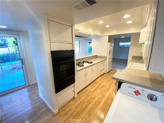 kitchen with white cabinetry, a healthy amount of sunlight, white appliances, light wood-type flooring, and sink