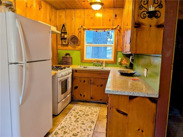 kitchen with white appliances, wooden walls, sink, wooden ceiling, and light tile patterned floors