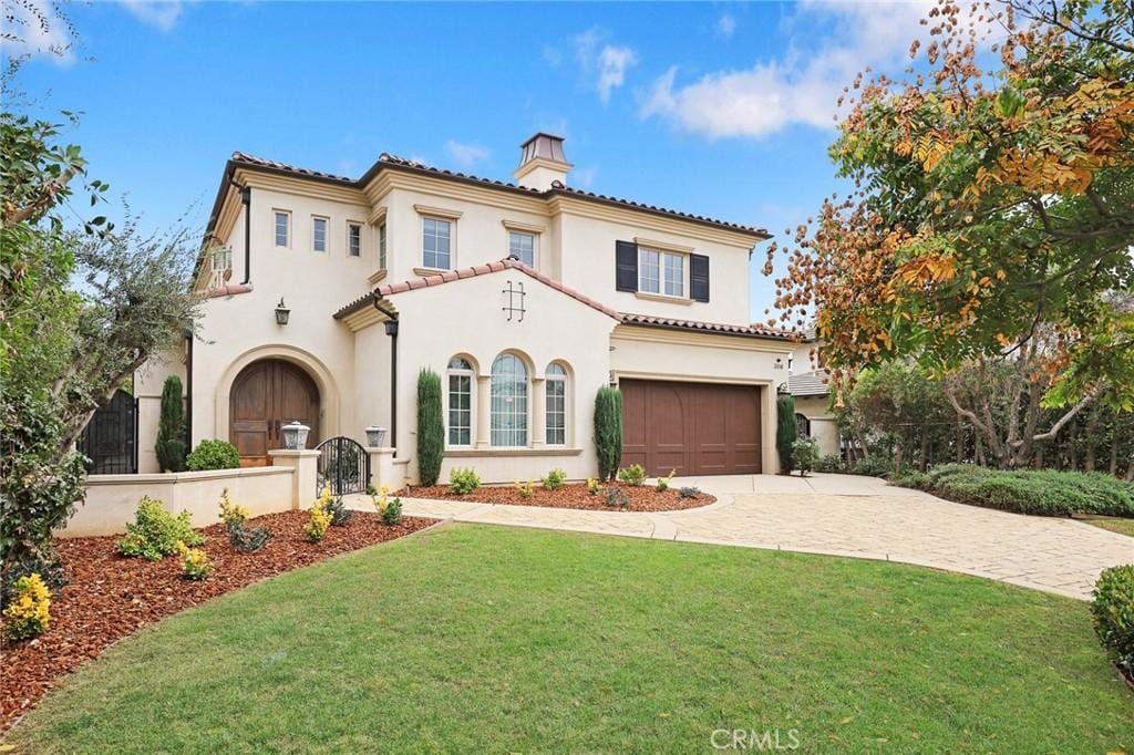 mediterranean / spanish house with a garage and a front lawn