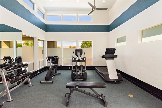 exercise room with ceiling fan and a towering ceiling