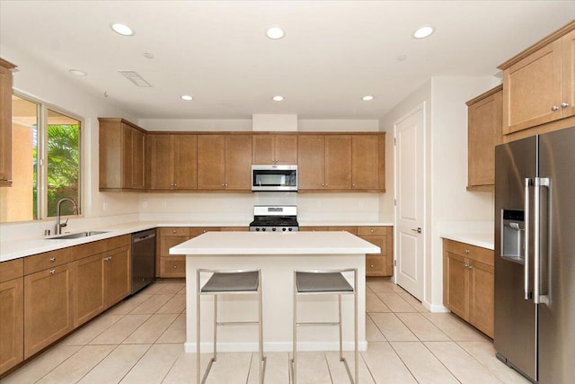 kitchen with light tile patterned flooring, appliances with stainless steel finishes, sink, and a center island