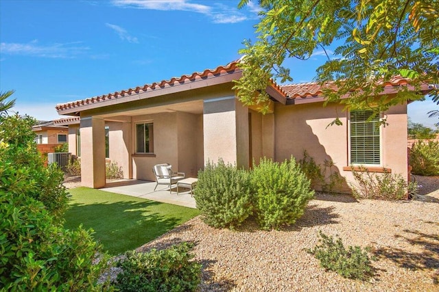 rear view of house with central AC, a lawn, and a patio