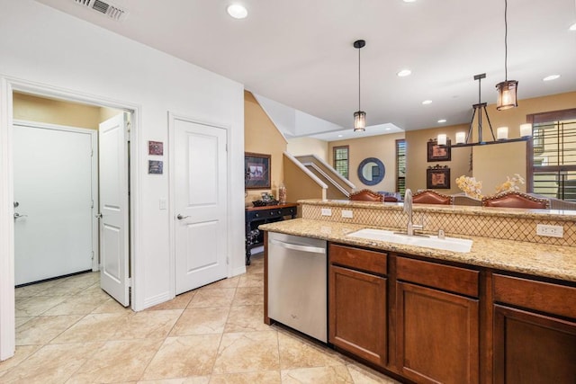 kitchen with stainless steel dishwasher, decorative light fixtures, sink, and light stone counters